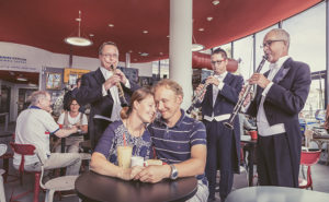 Kahden ihmisen herkkähetki Salacavala-kahviossa Kuopion kaupunginorkesterin muusikkoryhmän ympäröimänä.