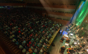 Katsomo täynnä yleisöä ja orkesteri lavalla Ruikonperän sinfonia -konsertissa 2023.